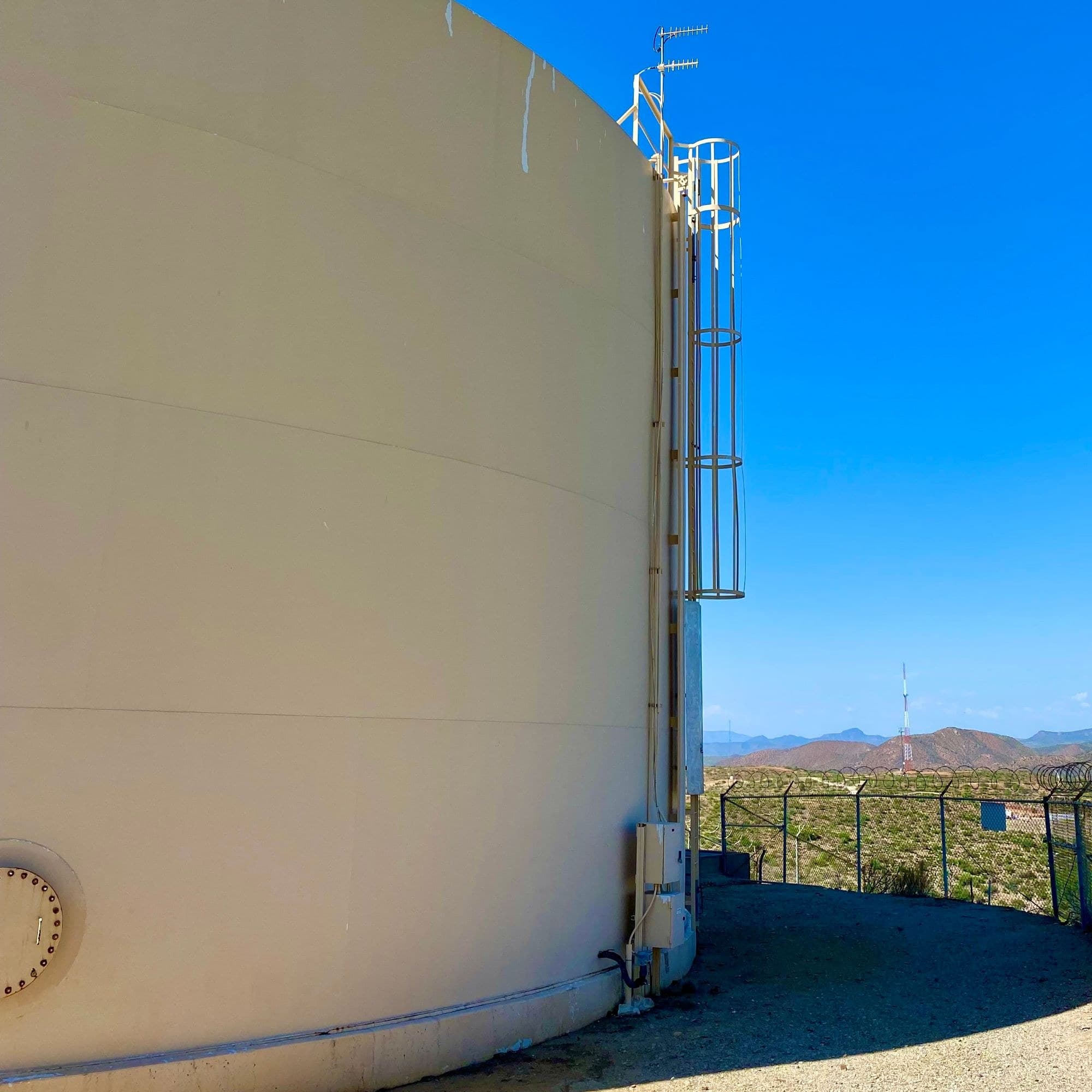 Desert water storage tank with Yagi radio antennas on the roof and control enclosures at its base